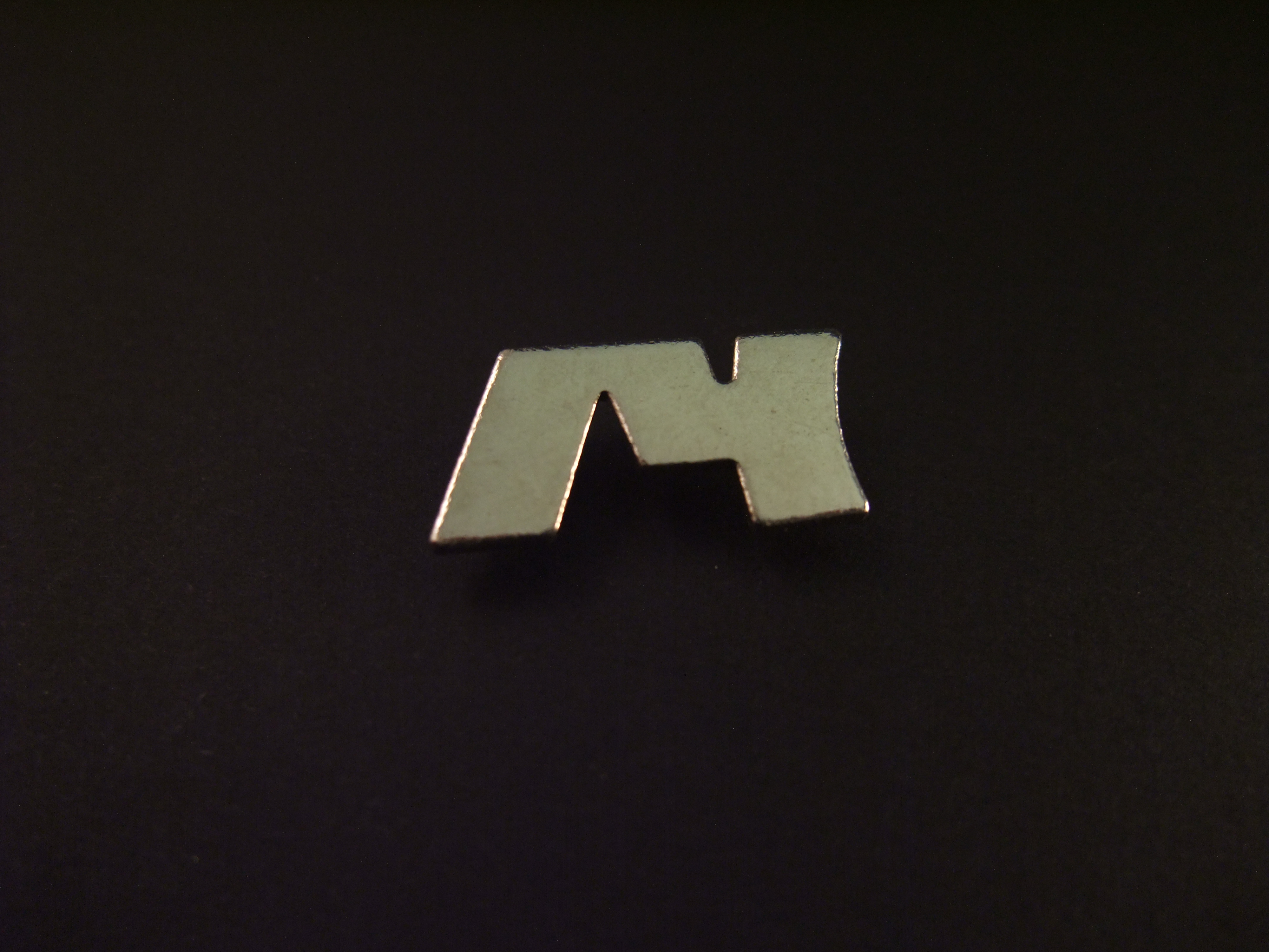 Scheve M onbekend logo zilverkleurig